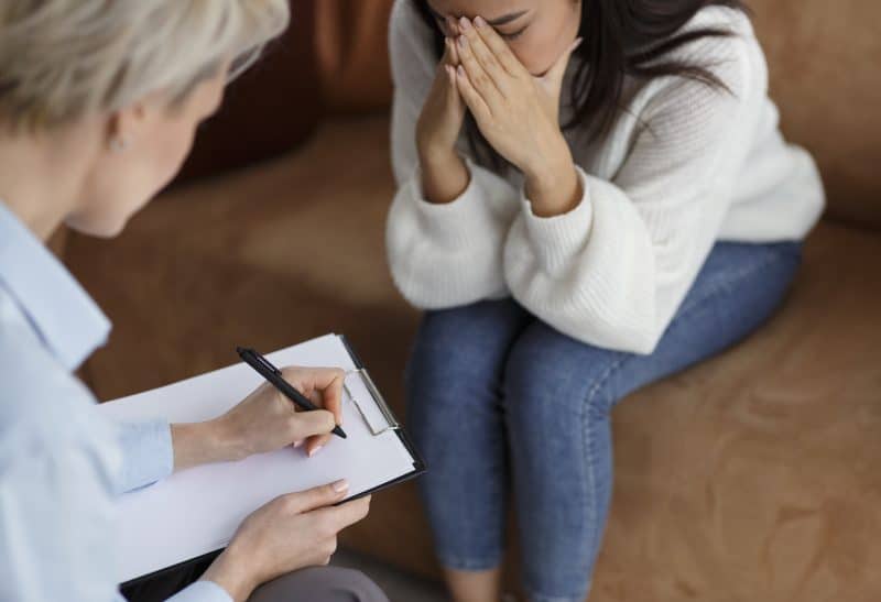 Psychologist Taking Notes Talking With Crying Woman In Office, Cropped